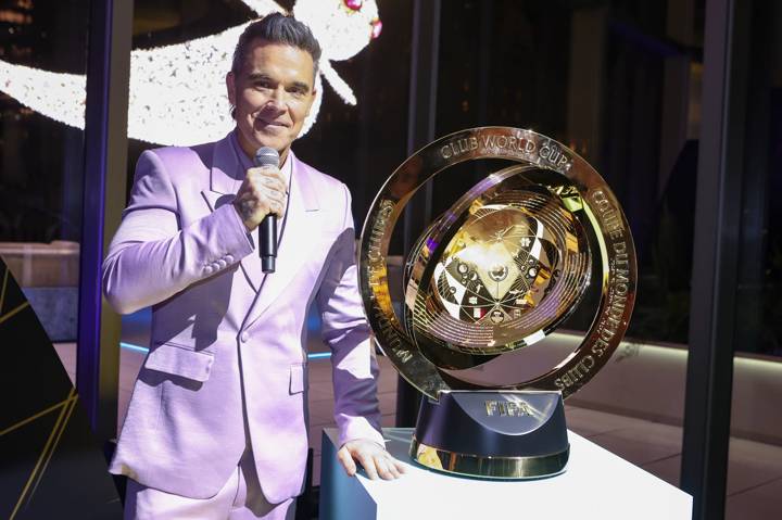 Robbie Williams poses next to the FIFA Club World Cup Trophy 